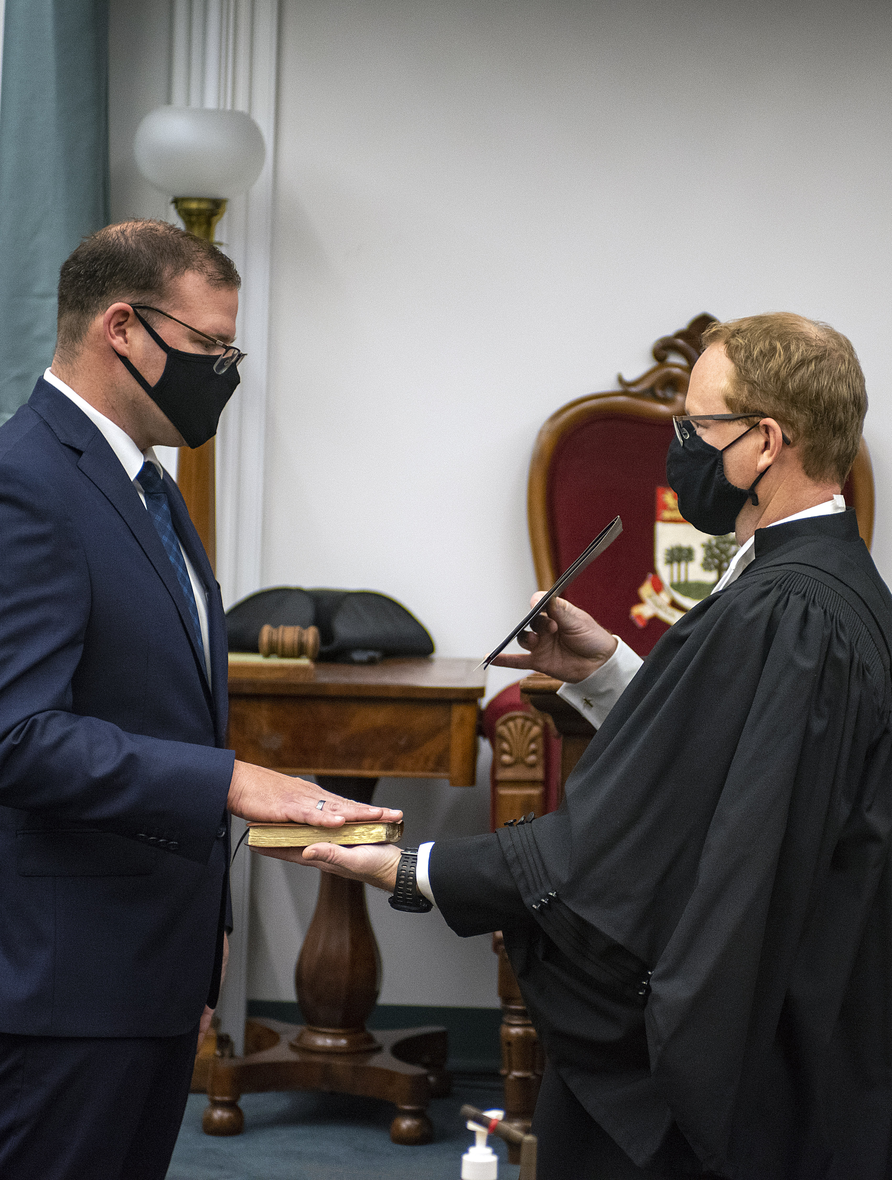 A photo of Zach Bell swearing the oath of allegiance. The oath is being administered by Joseph Jeffrey, Clerk of the Legislative Assembly.